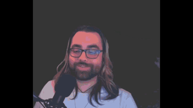 a man wearing glasses and headphones stands in front of a microphone