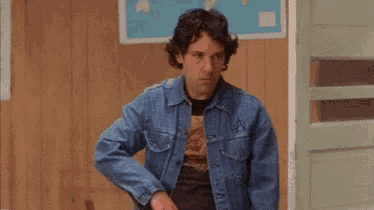 a man wearing a denim jacket is putting on sunglasses .