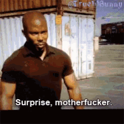 a man in a black shirt is standing in front of a building and says surprise motherfucker
