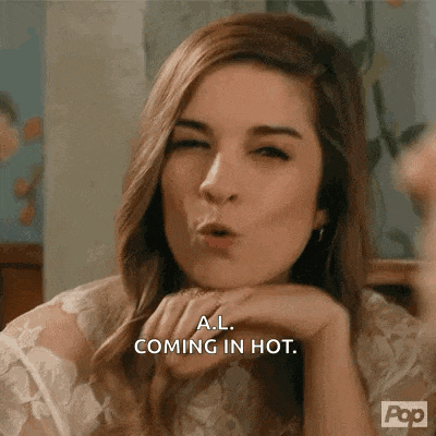 a woman is making a funny face and says a.l. coming in hot .