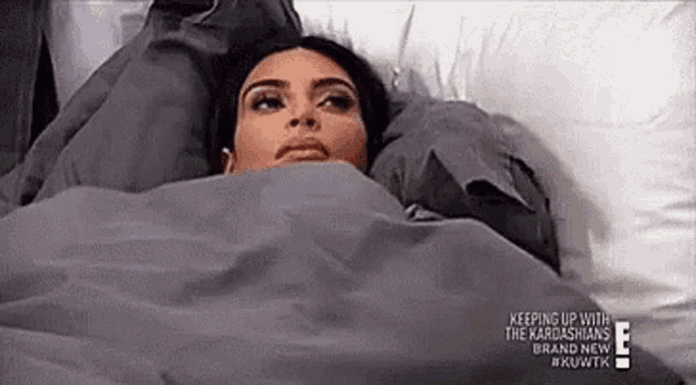 a woman is laying in a bed with a blanket on her head .