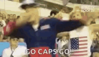 a man in an american flag shirt is standing in front of a crowd of people .