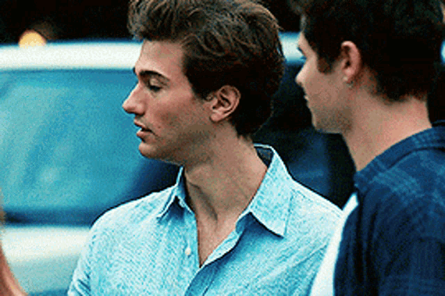 two young men in blue shirts are standing next to each other .