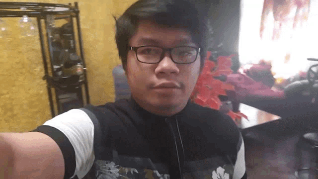 a man wearing glasses takes a selfie in front of a wine shelf