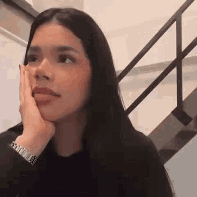 a woman is sitting on a staircase with her hand on her chin .