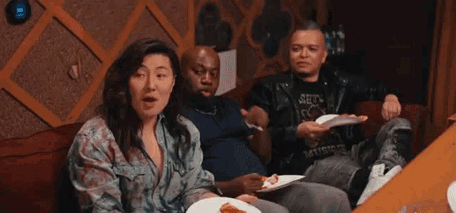 a group of people are sitting on a couch eating pizza together .