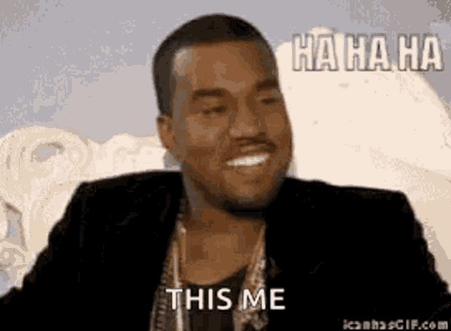 a man in a suit is laughing and saying `` this me '' while sitting on a couch .