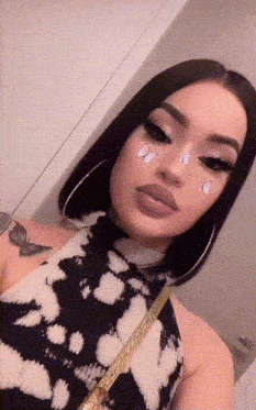 a woman with a butterfly tattoo on her shoulder is taking a selfie