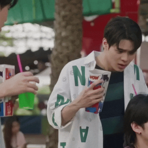 a man wearing a shirt with the letter n on it is holding a cup