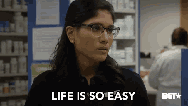 a woman wearing glasses is standing in front of a sign that says " life is so easy "