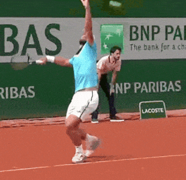 a man playing tennis in front of a bnp paribas ad