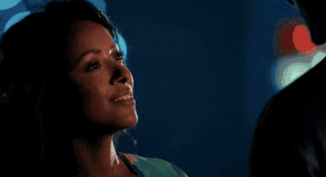 a woman is smiling in a dark room with lights behind her
