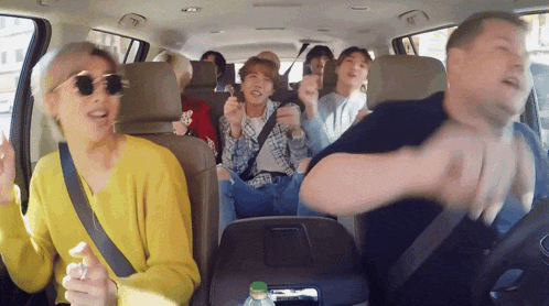 a group of people are sitting in the back seat of a car dancing