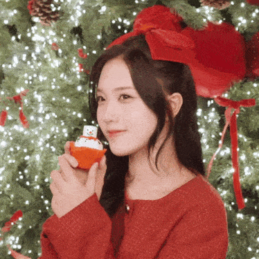 a woman in a red sweater is holding a cupcake with a snowman on it