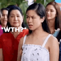 a woman in a white tank top is standing in front of a crowd of people .