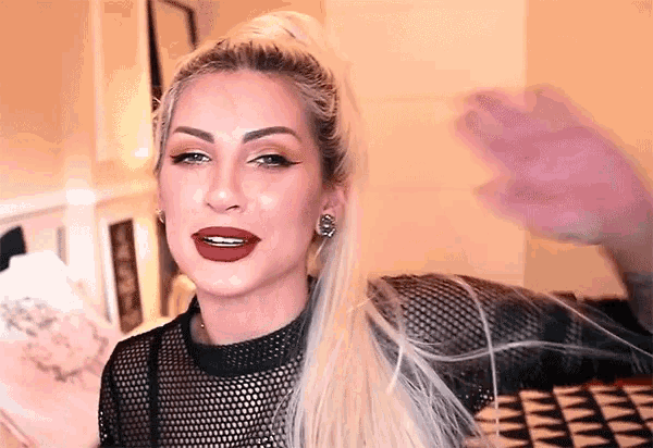 a woman with long blonde hair wearing a black top and red lipstick