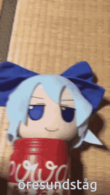 a stuffed doll with a blue bow is sitting in a can of coca cola