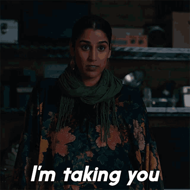 a woman wearing a scarf and a floral shirt says i 'm taking you