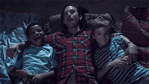 a man is laying on a bed with two boys .