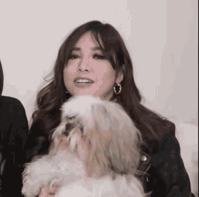 a woman is holding a small white dog on her lap .