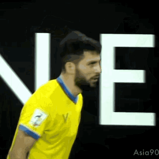 a man in a yellow shirt is standing in front of a large white letter e