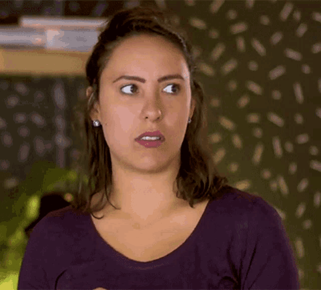 a woman wearing a purple shirt is making a funny face