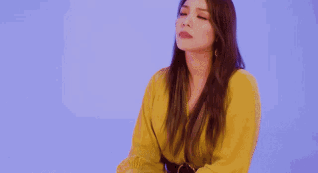 a woman with long hair is wearing a yellow shirt and making a funny face .