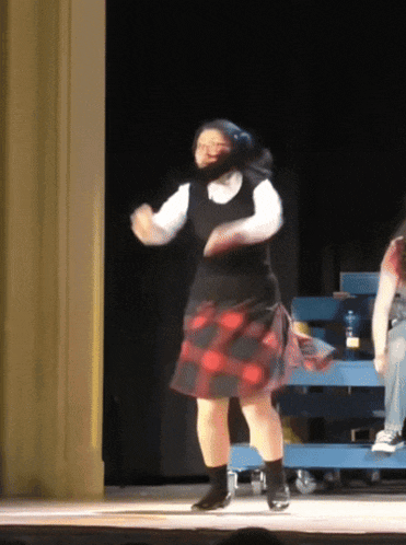 a woman in a plaid skirt dancing on a stage