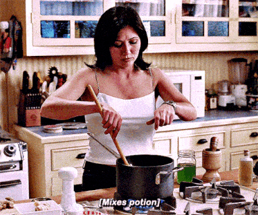 a woman in a white tank top is stirring a pot with a wooden spoon .