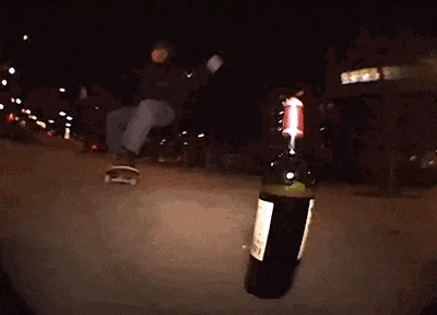 a person is riding a skateboard with a bottle of wine next to them .