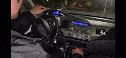 a person is driving a car with a sticker on the dashboard that says ' x '