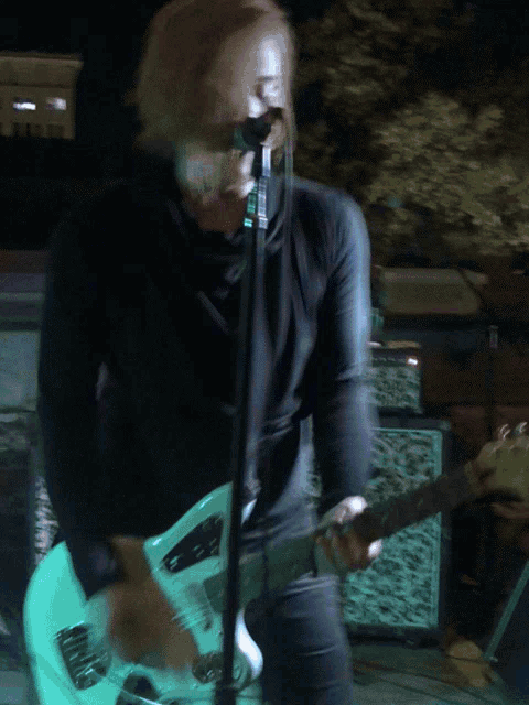 a man sings into a microphone while playing a guitar