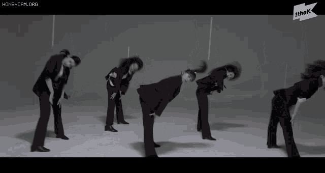 a group of people in suits are doing a dance routine with the k logo in the corner