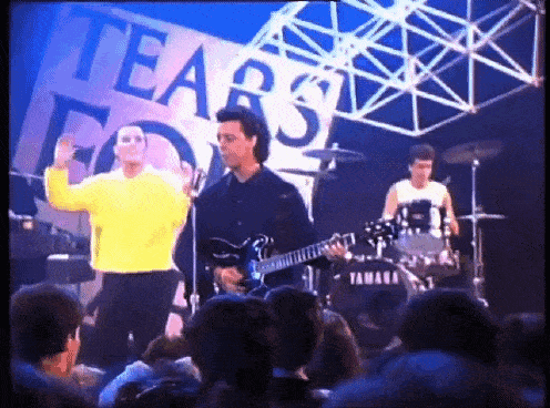 a man playing a guitar in front of a sign that says " tears "