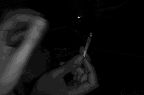 a black and white photo of a person 's hand holding something in a dark room .