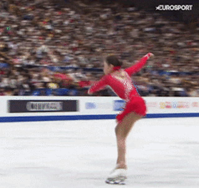 a woman in a red dress is ice skating in front of a crowd with eurosport written on the bottom right