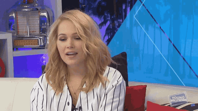 a woman sitting on a couch with a young hollywood sign on the couch