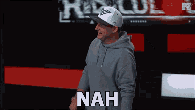a man wearing a hat and a hoodie says the word nah