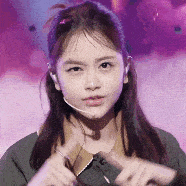 a young woman wearing a microphone and a ponytail looks at the camera