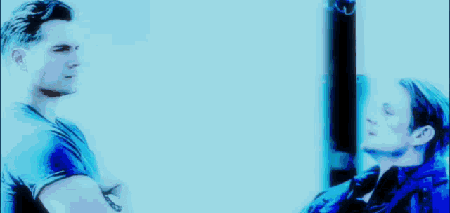 two men standing next to each other in a blue light