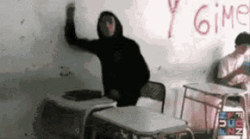 a man in a black hoodie is standing in front of a white board with the word gimp written on it .
