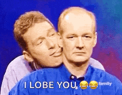two men are standing next to each other and one of them is kissing the other 's cheek .