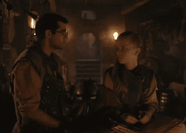 two men standing next to each other in a dark room with candles on the wall