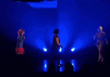 a girl singing into a microphone and a man dancing on a stage with blue lights