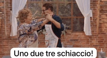 a man and a woman are dancing in front of a brick wall in a kitchen .