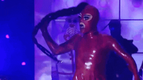 a man in a red mask is singing into a microphone .
