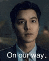 a man in a suit and tie is looking at the camera with the words `` on our way '' above him .
