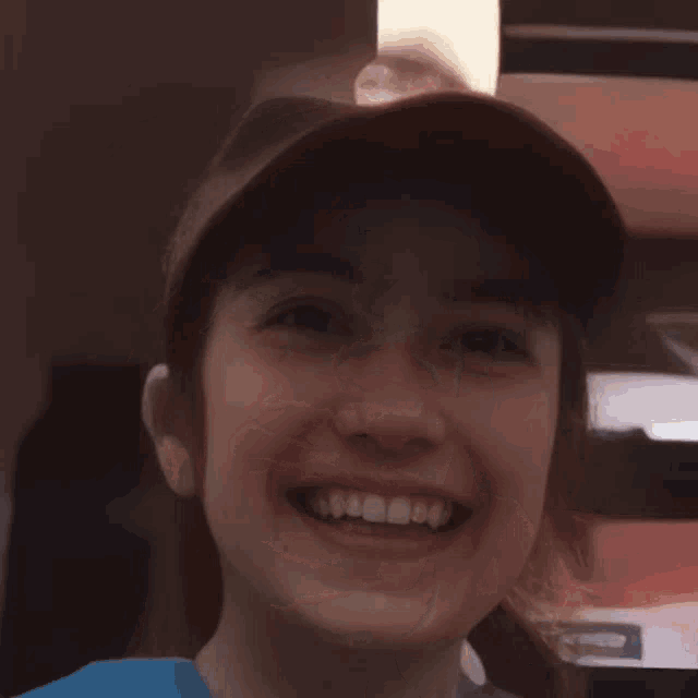 a young boy wearing a baseball cap is smiling