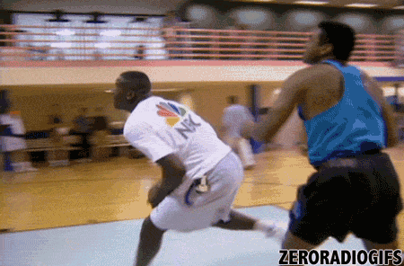 a man in a nbc shirt is dribbling a basketball