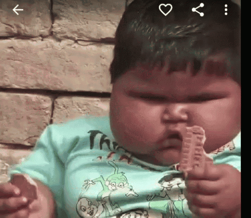 a baby is eating a cookie and making a face .